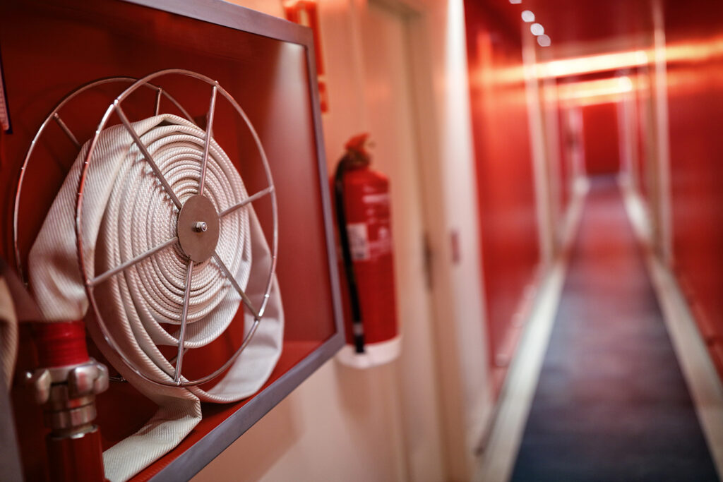 Fire extinguisher and hose reel in hotel corridor.