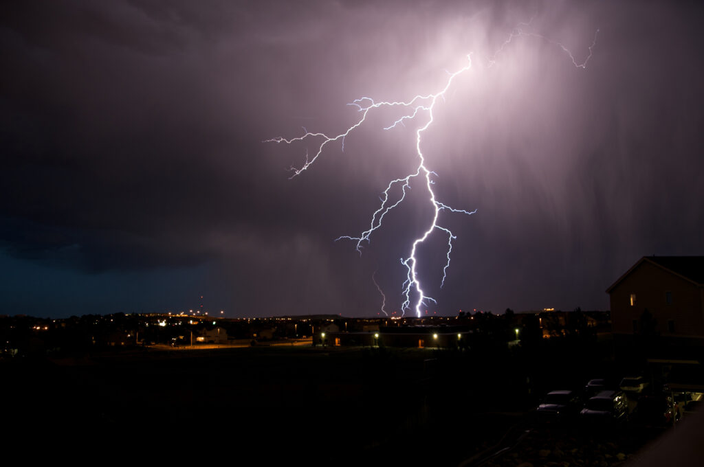 Weitwinkelaufnahme einer Stadt mit einem großen Blitz am Himmel.